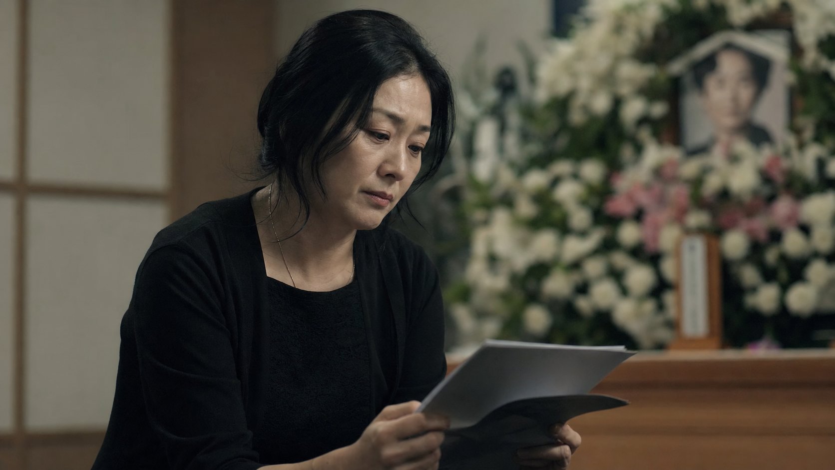 검안 서류를 손에 들고 침통하게 앉아 있는 유가족