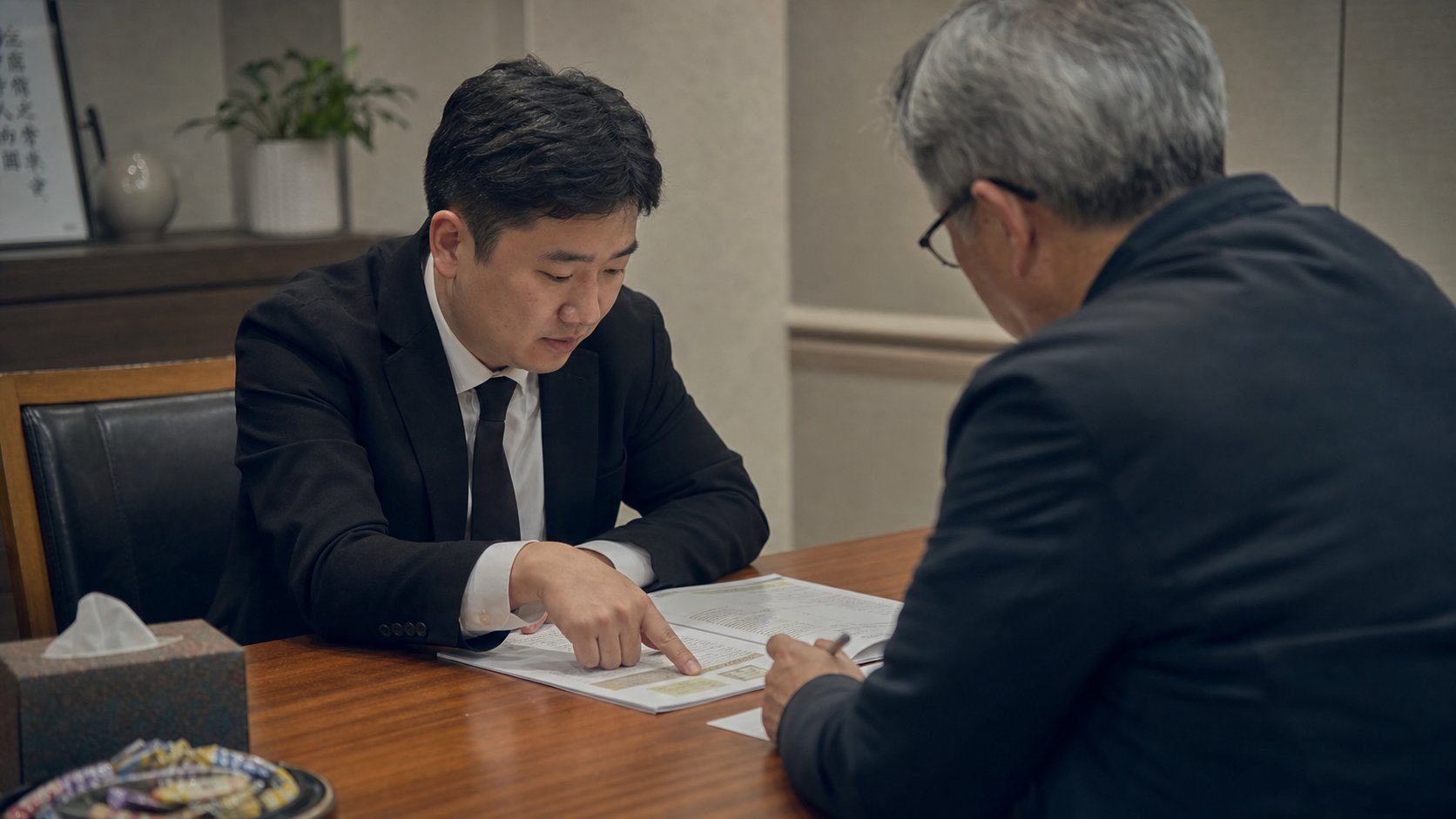 상조 상담실에서 직원이 약관 책자를 설명하고 가족이 메모하는 모습