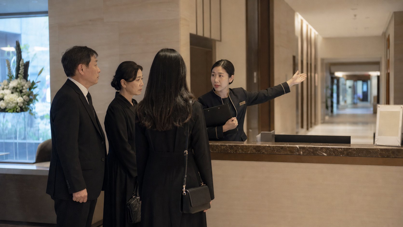 장례식장 로비에서 가족이 도착해 직원과 안치 절차를 안내받는 장면