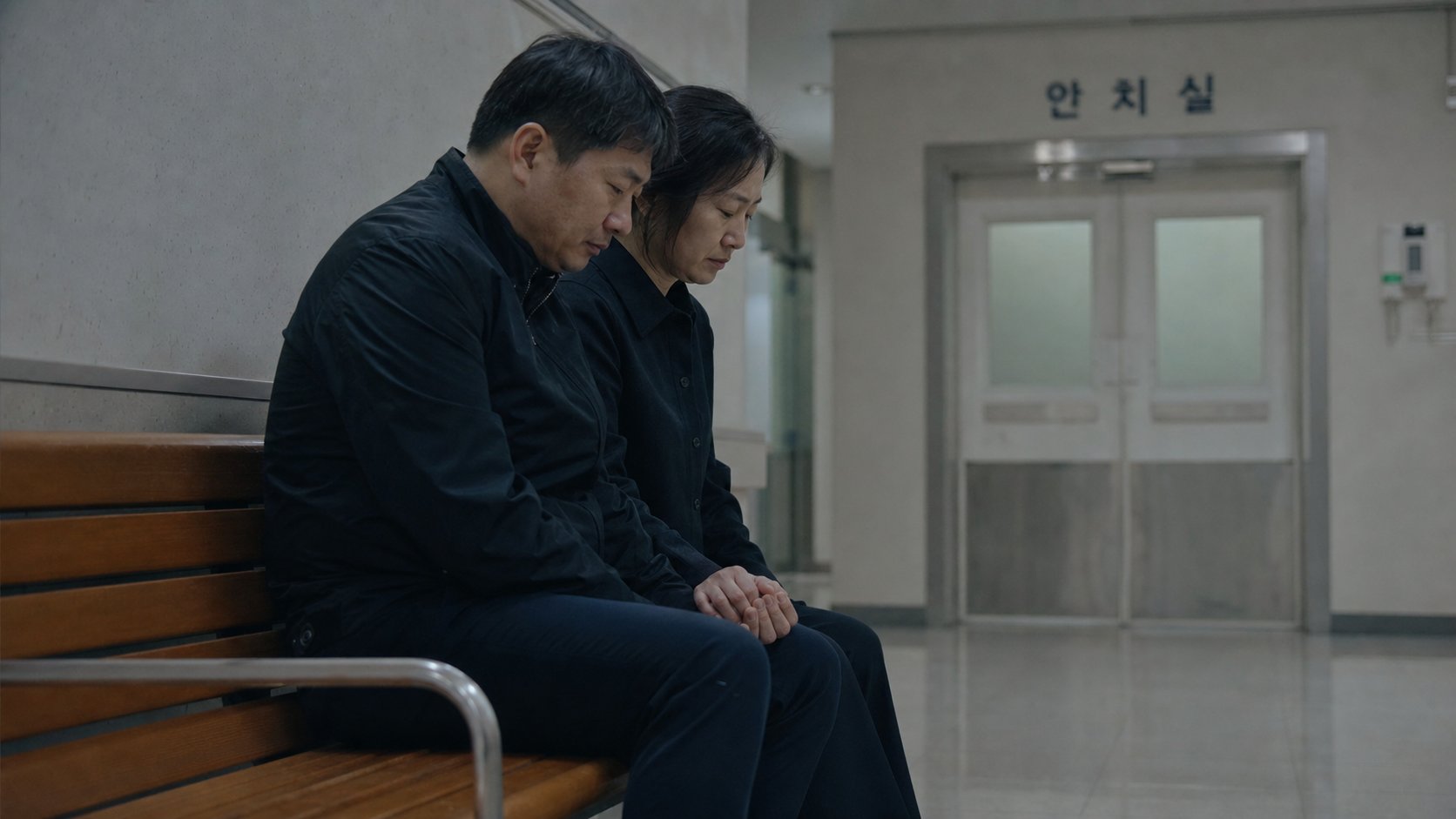 병원 복도에서 가족이 손을 잡고 조용히 기다리는 장면