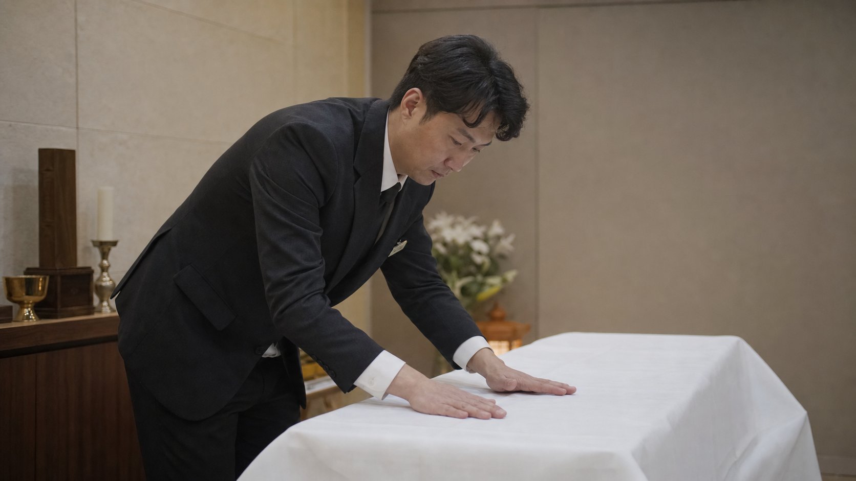 장례지도사가 흰 천으로 고인을 정돈하는 모습