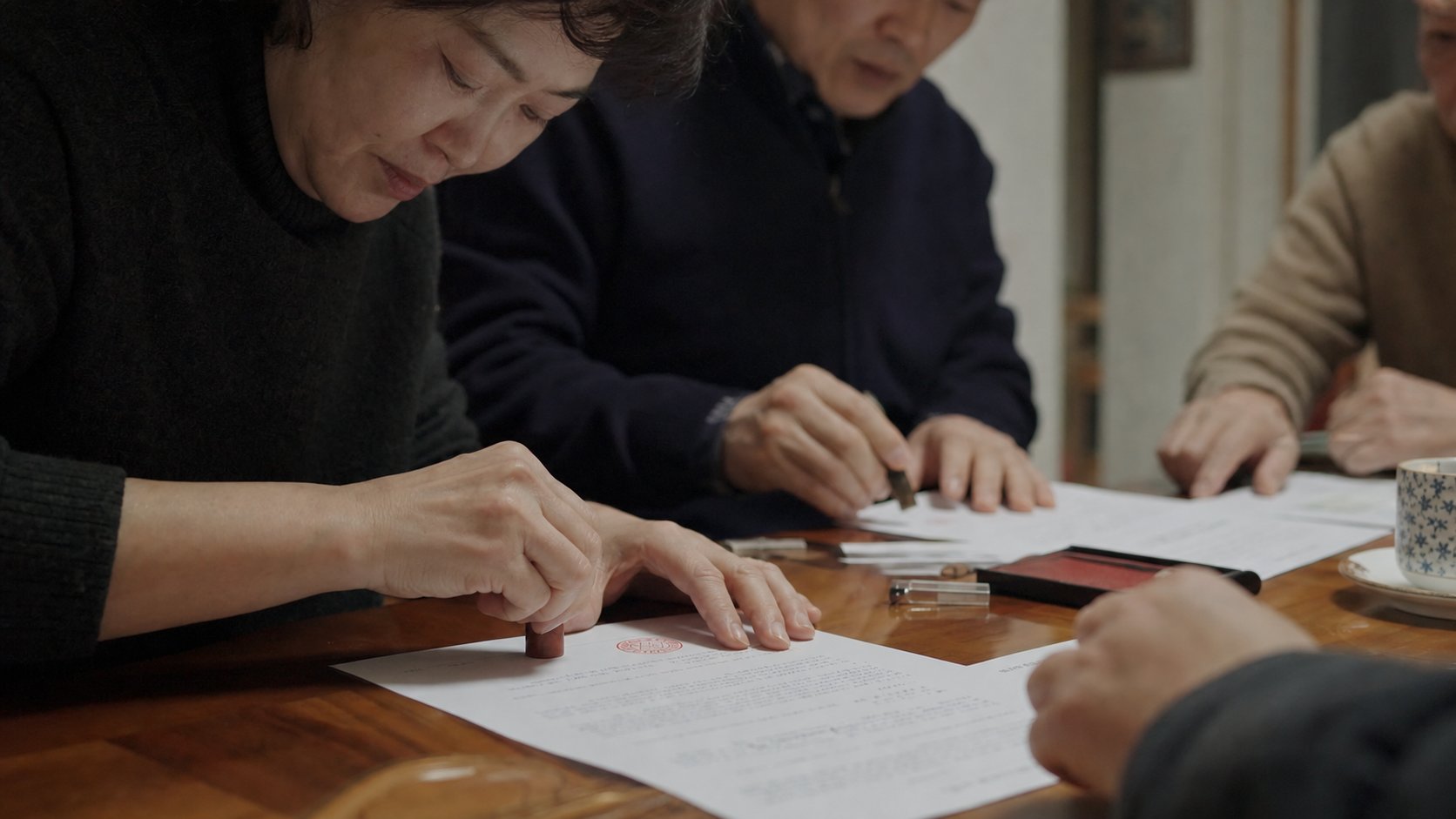 상속재산 분할협의서에 서명하고 인감도장을 날인하는 손