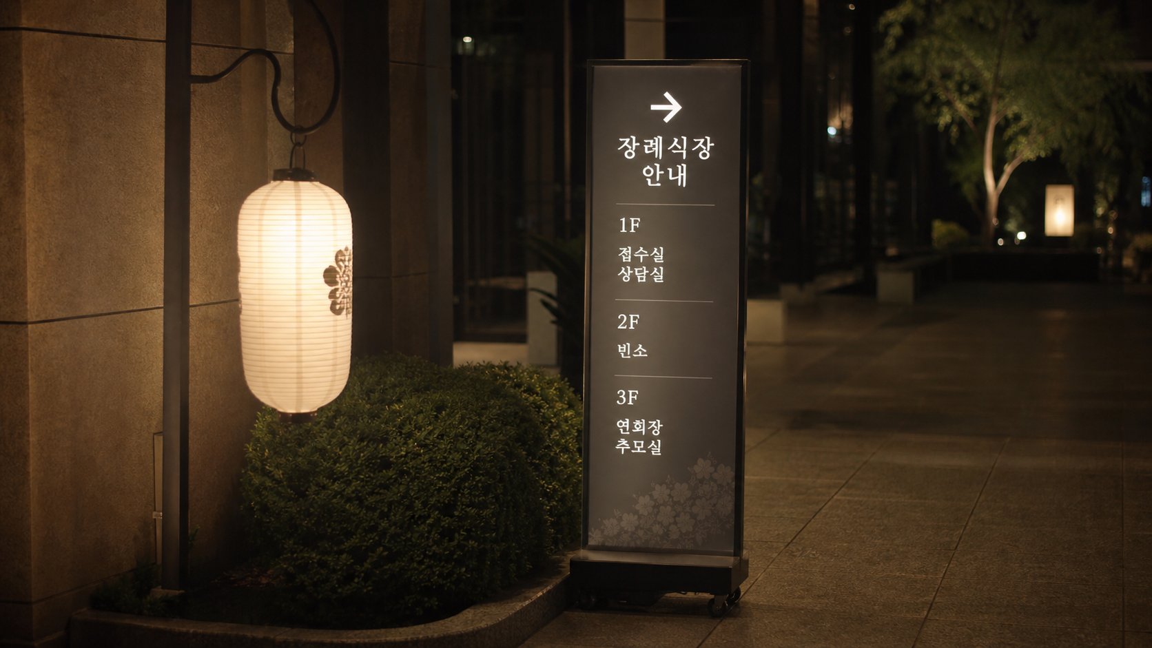 장례식장 입구에 흰 등과 안내 표지가 환하게 불을 밝힌 현대 빈소 입구 장면
