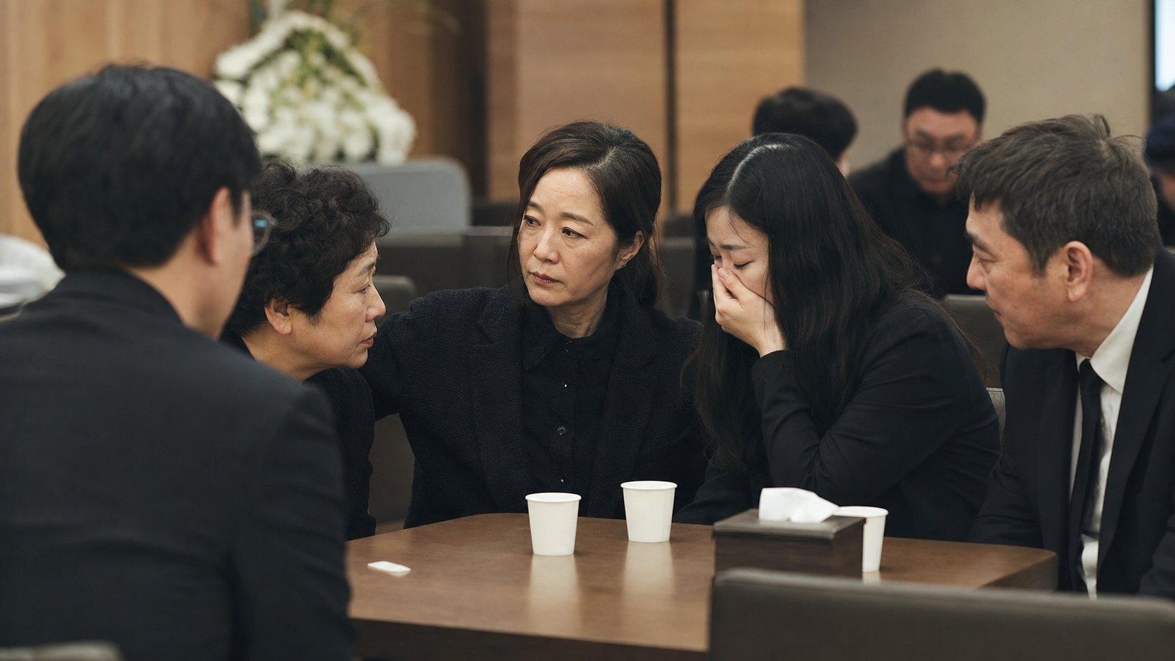 검은 옷을 입은 친척들이 접객실에 모여 차분히 이야기 나누는 모습
